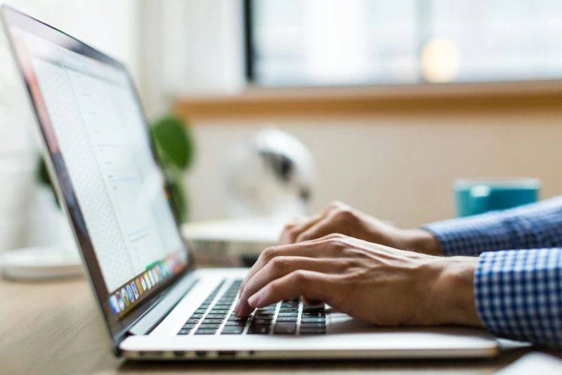 Person working on a laptop laptop managing digital documents, representing NDIS service agreement reviews and signed files.